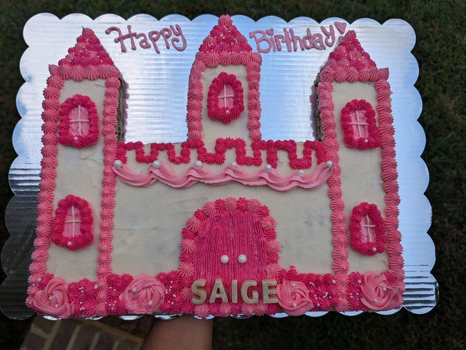 Pink castle Happy Birthday cookie cake with piped pink rosettes on a silver scalloped board